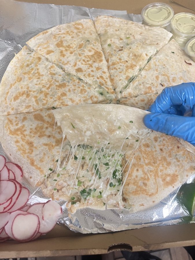 Large quesadilla sliced into wedges with melted cheese pull