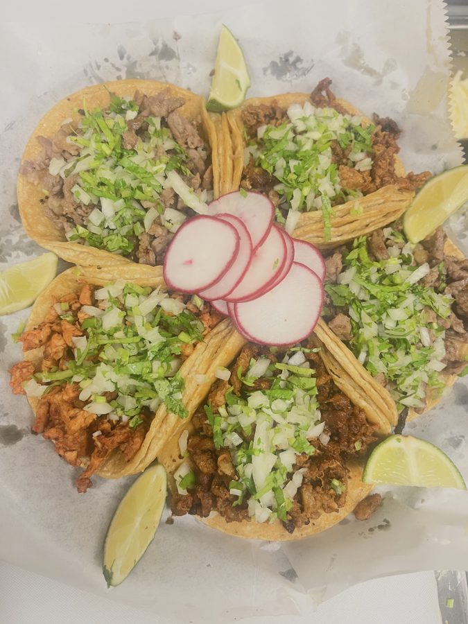 Street tacos topped with onion, cilantro, radish and lime